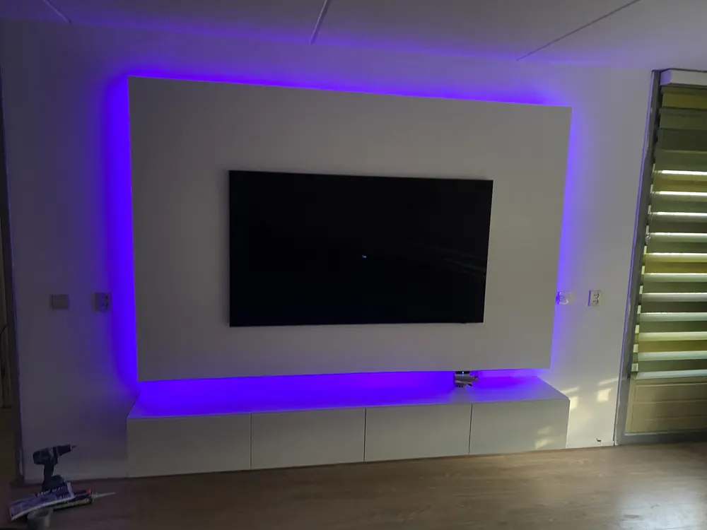 Strakke minimalistische witte zwevende tv-wand met paarse LED achtergrondverlichting